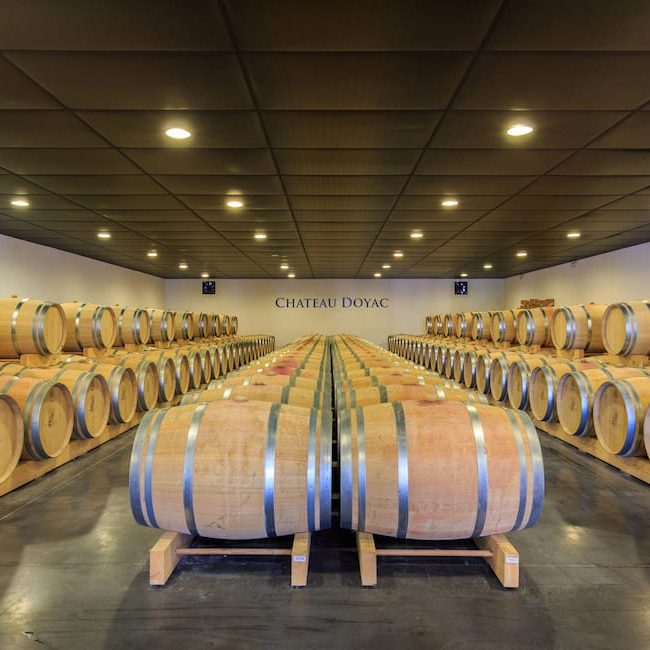 Chateau Doyac wine cellar with barrels in Gironde